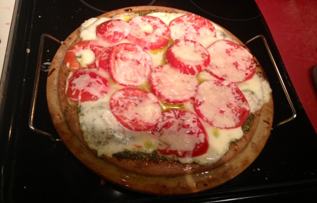 Homemade tomato and mozzarella pizza with a pesto base instead of marinara sauce.